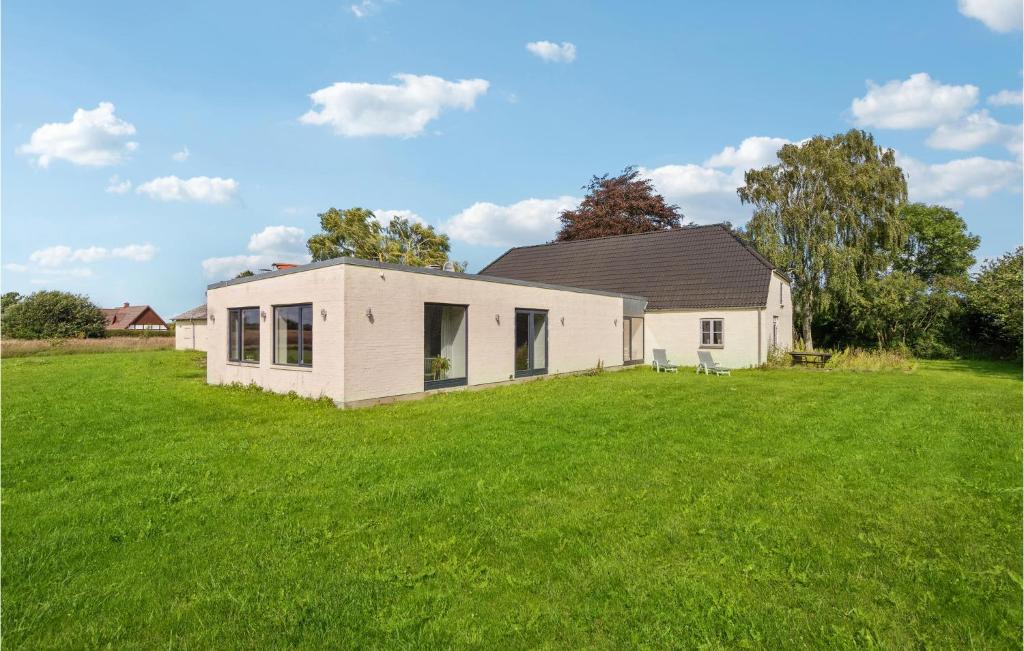 a white house in a field with a grass yard at 5 Bedroom Cozy Home In Odense N in Odense