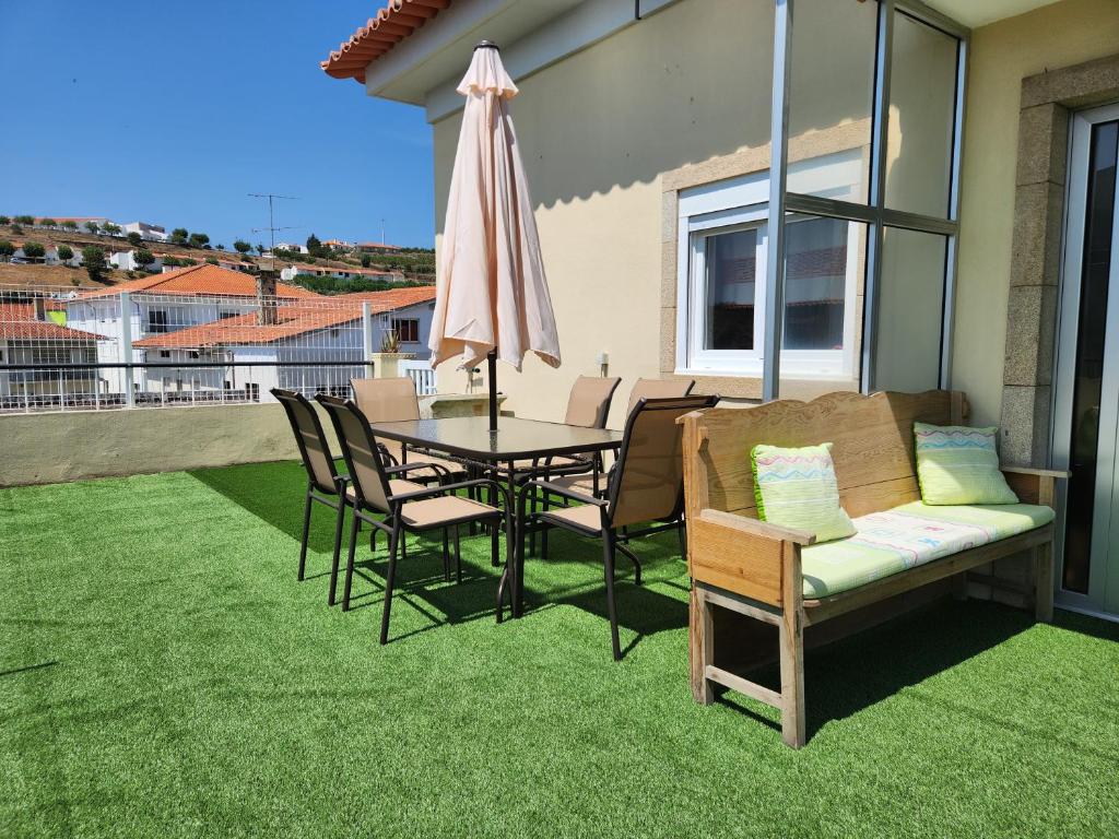 a patio with a table and a couch and an umbrella at Casa da Avó Aninhas in Freixo de Espada à Cinta