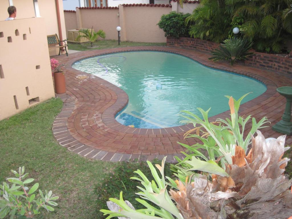 a swimming pool with a brick pathway around it at Swallows Nest B&B in Margate