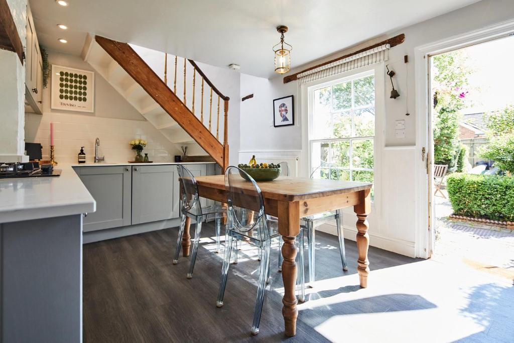 a kitchen with a wooden table and a staircase at Cottage on The Croft in Hungerford