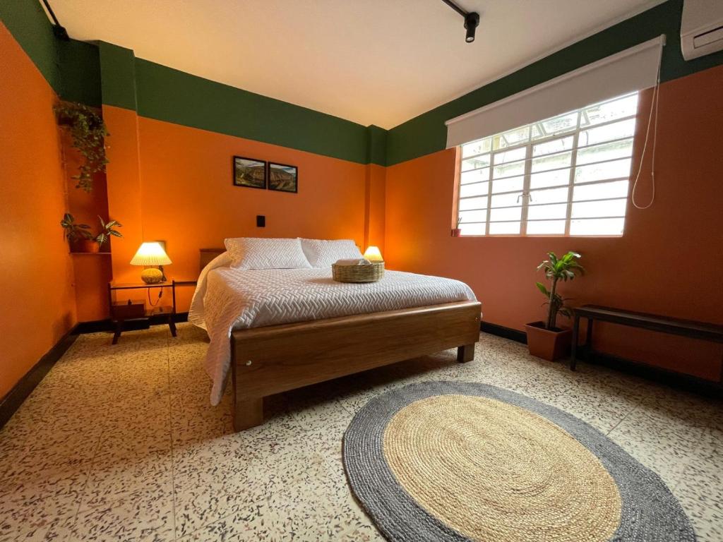 ブカラマンガにあるLa Bonita Guesthouseのオレンジと緑の壁のベッドルーム1室、ベッド1台が備わります。