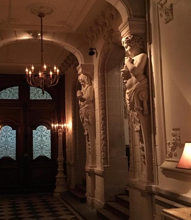 un couloir dans un bâtiment avec une statue sur le mur dans l'établissement Maison d'Hercule, à Mayenne