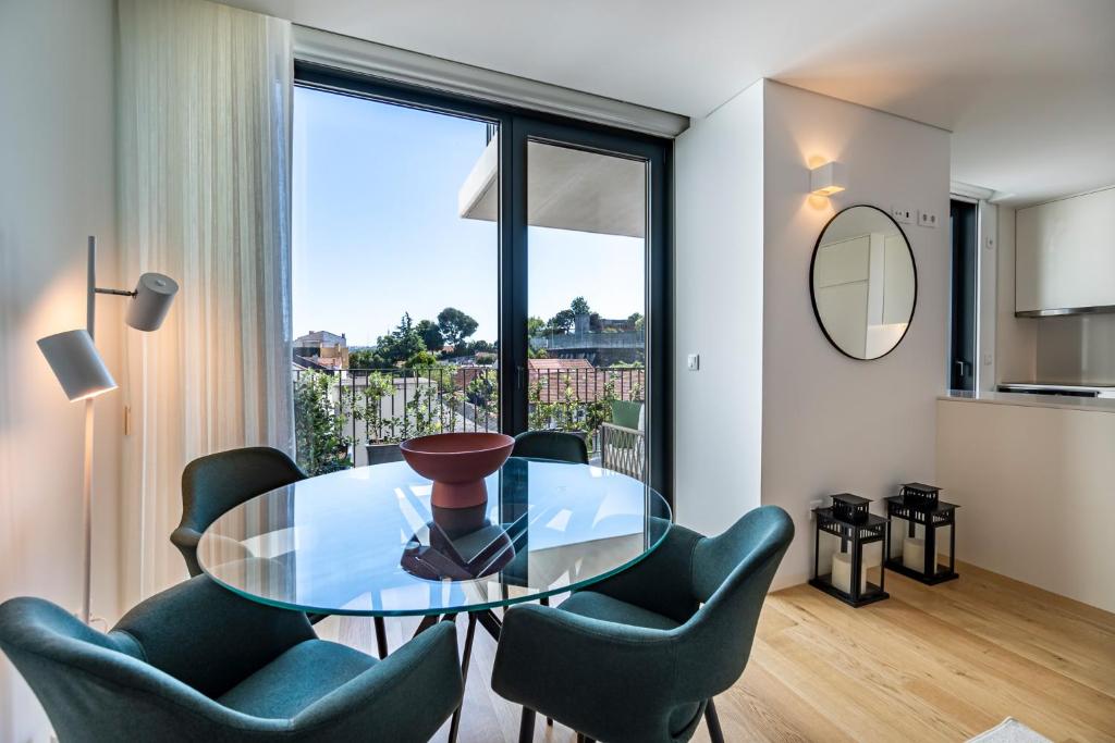 uma sala de jantar com uma mesa de vidro e cadeiras em BONFIM LIVING - Great location, al fresco dining and free private parking no Porto