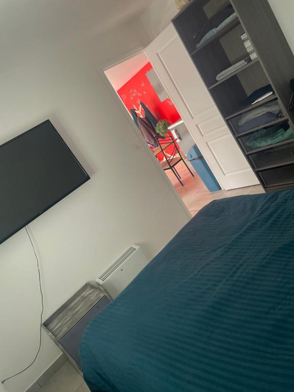 een slaapkamer met een bed en een flatscreen-tv bij L'espace détente in Beuvry