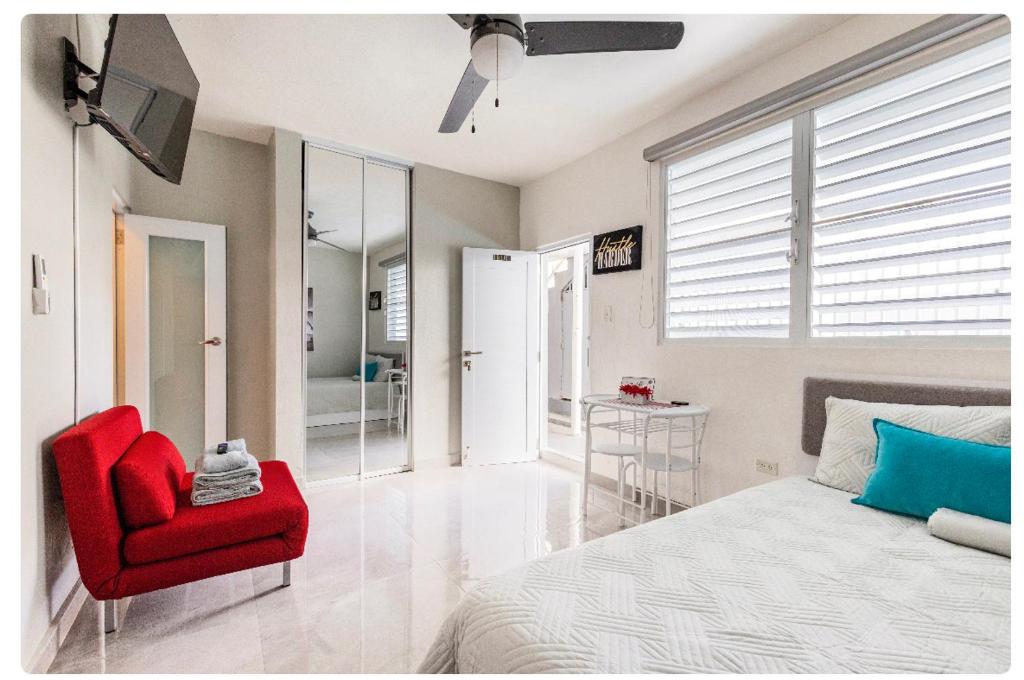 1 dormitorio con 1 cama y 1 silla roja en Ocean Pearl en San Juan
