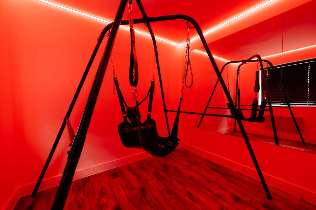 una habitación con una pared roja con dos cadenas en Casa Amor - Kinky Hotel UK, en Southampton