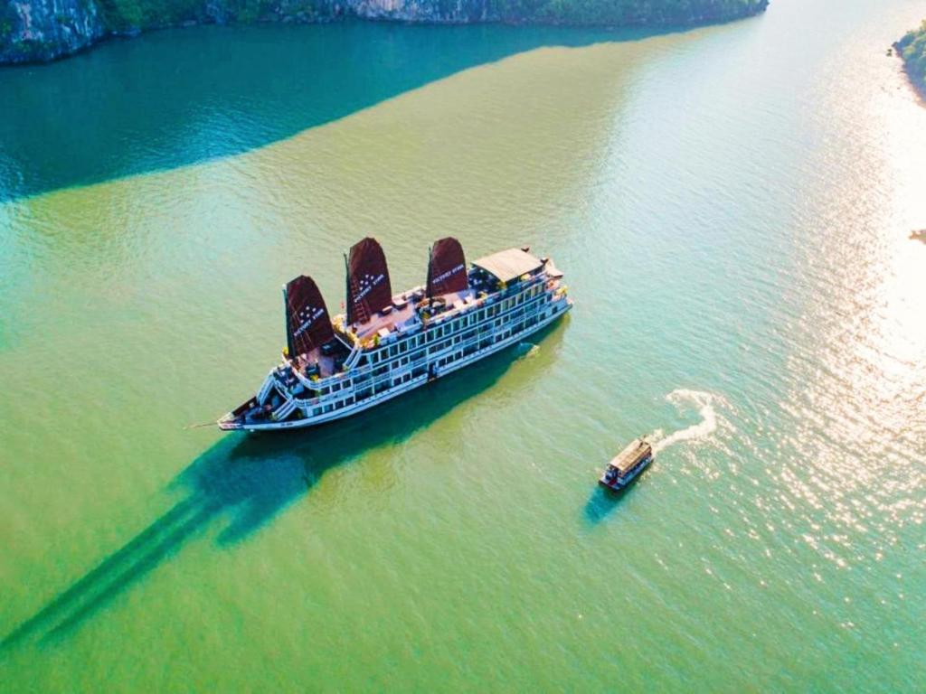 um navio de cruzeiro na água com um pequeno barco em Victory Boutique Cruise em Ha Long