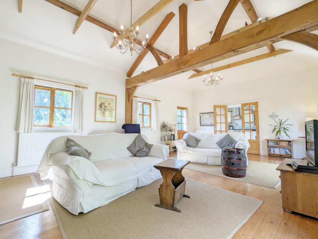 The Cottage at Hale Hill Farm, Pulborough في بولبورو: غرفة معيشة مع أريكة بيضاء وطاولة
