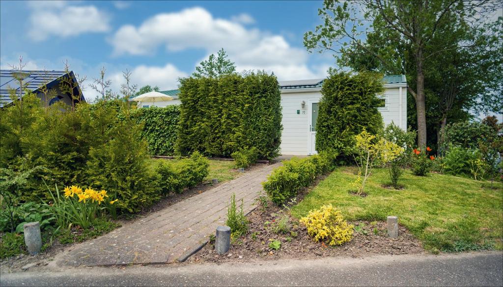 a garden with a brick walkway in front of a house at chalet 22 in Sint Annaland