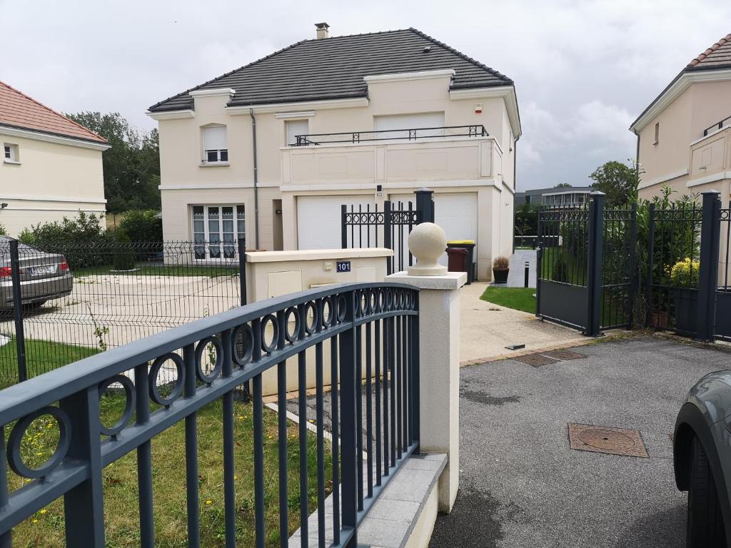 ein weißes Haus mit einem Tor und einem Zaun in der Unterkunft bienvenus chez Éric à Montévrain in Montévrain