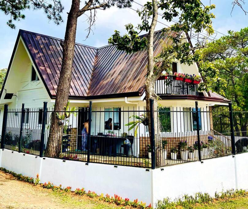 una casa blanca con una valla y un árbol en Melia's House Baguio - Nature Home for Rent, en Baguio
