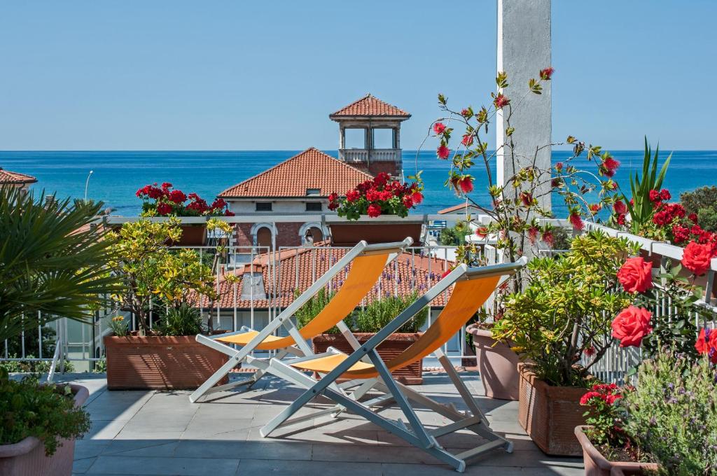 ein Paar Stühle auf einem Balkon mit Blumen in der Unterkunft Hotel Scandinavia in Marina di Massa