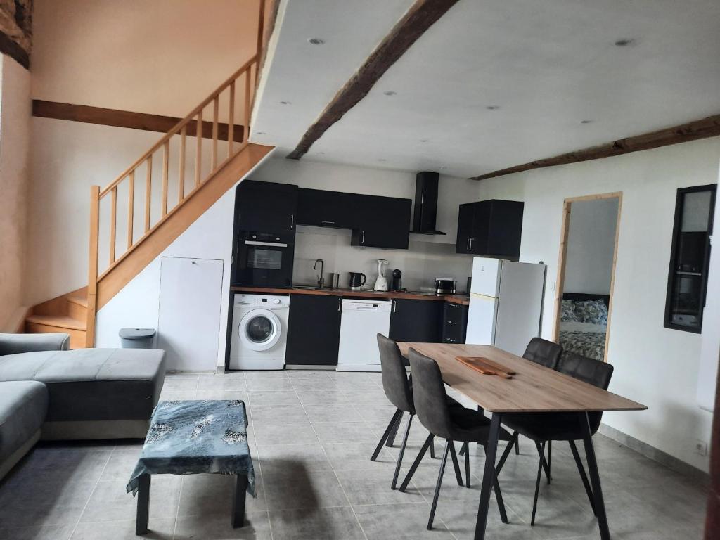 uma cozinha e sala de estar com uma mesa de madeira e cadeiras em Chez Line et Pierre: Appartement spacieux, lumineux et équipé em La Bastide-de-Sérou