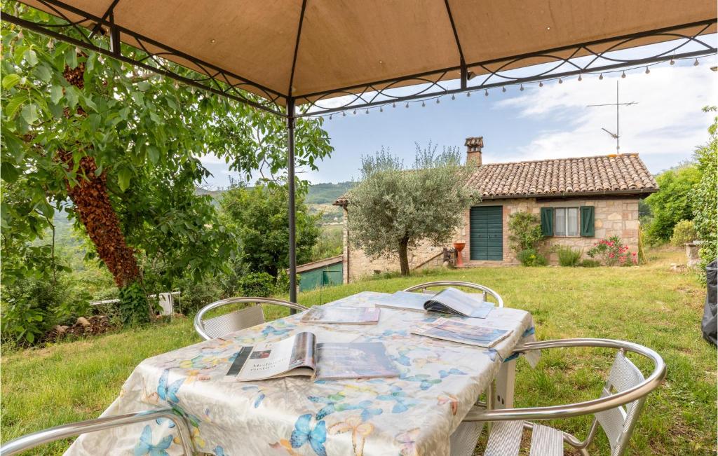 uma mesa e cadeiras debaixo de um guarda-sol num quintal em 2 Bedroom Beautiful Home In Monte C,di Vibio Pg em Monte Molino