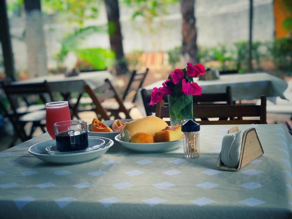 una mesa con platos de comida y flores. en Riacho do Recanto Pousada, en Barreirinhas
