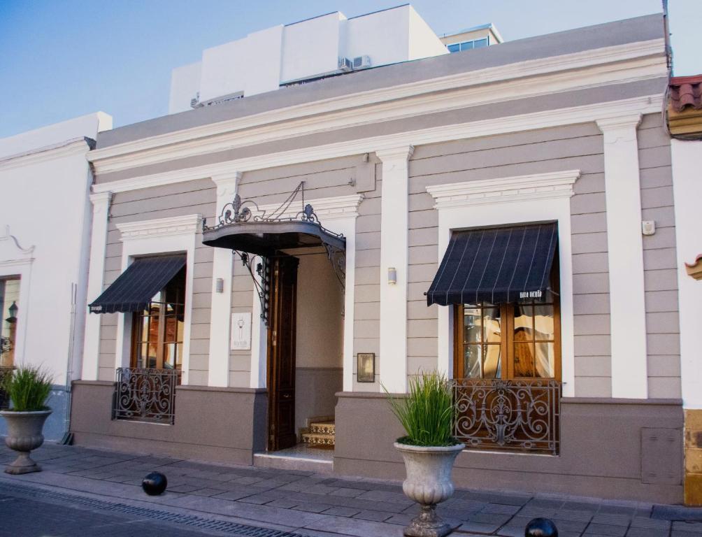 a white building with black awnings and windows at Villa Vicuña Hotel Boutique in Salta