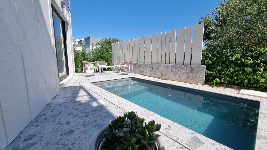 ein Pool neben einem weißen Haus in der Unterkunft Delta House - Beta apartment in Zadar