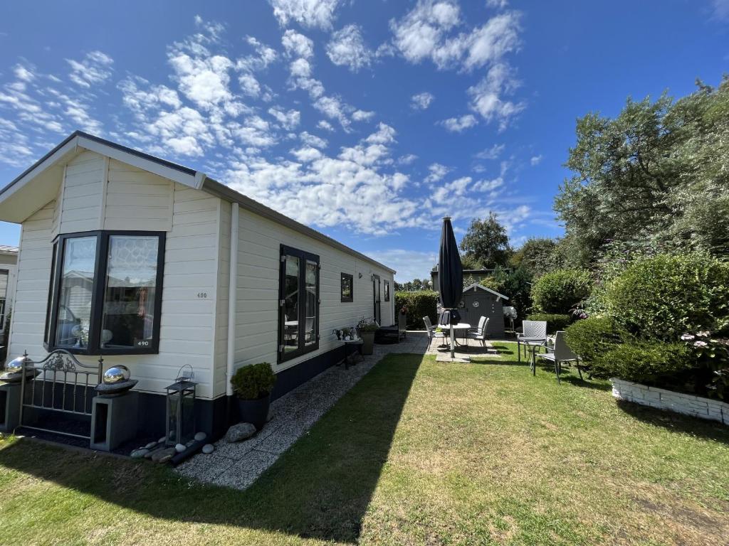a white tiny house with a yard at Zandput 490 - Camping de Zandput in Vrouwenpolder
