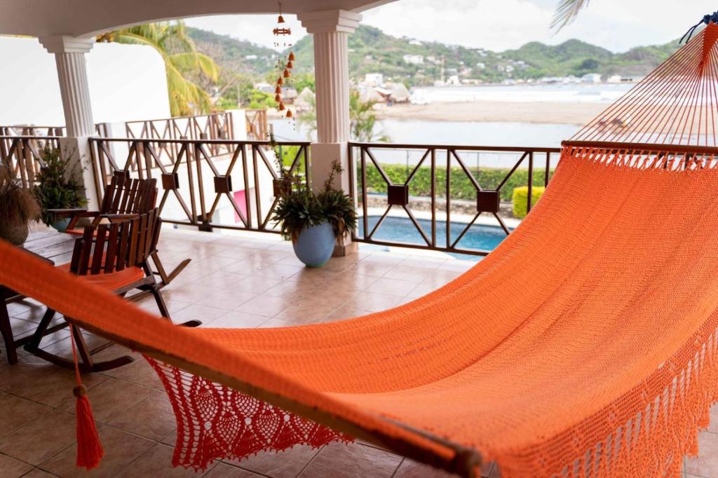 eine orangefarbene Hängematte auf einer Veranda mit Blick auf den Strand in der Unterkunft HC Liri Hotel in San Juan del Sur