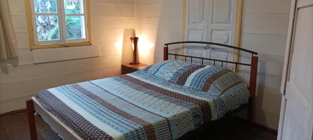 a bedroom with a bed and a lamp and a window at La Pendule d'Argent in Salazie