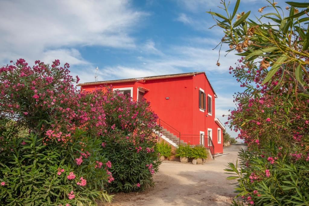 a red building with pink flowers in front of it at Agriturismo L'Istrice di Giò in Montalto di Castro