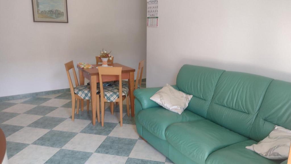 ein Wohnzimmer mit einem grünen Sofa und einem Tisch in der Unterkunft Casa Smeralda in Ameglia