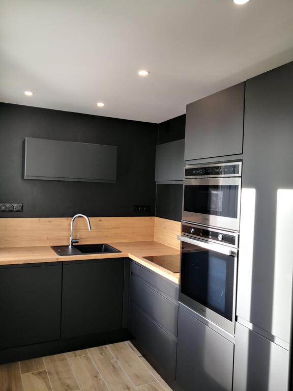a black kitchen with a sink and a stove at Studio moderne, place parking privé, emplacement idéal à 100 m du lac. in Annecy