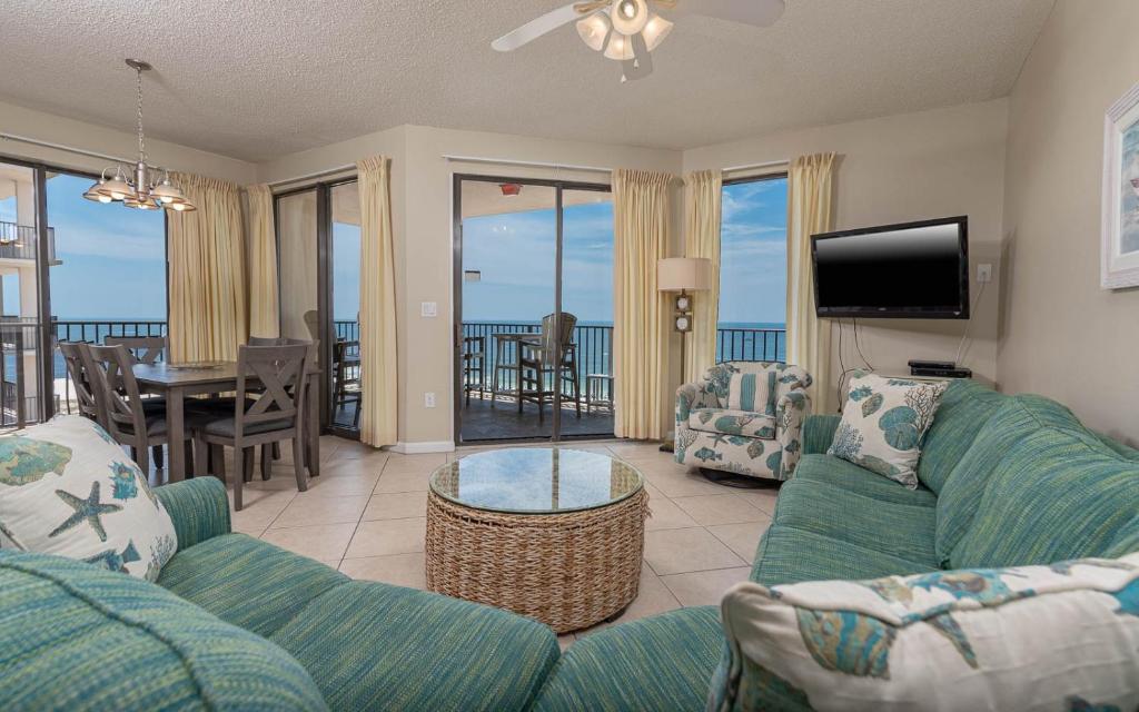 Una sala de estar con un sofá y sillas y un televisor. en Phoenix East 1111 condo, en Orange Beach