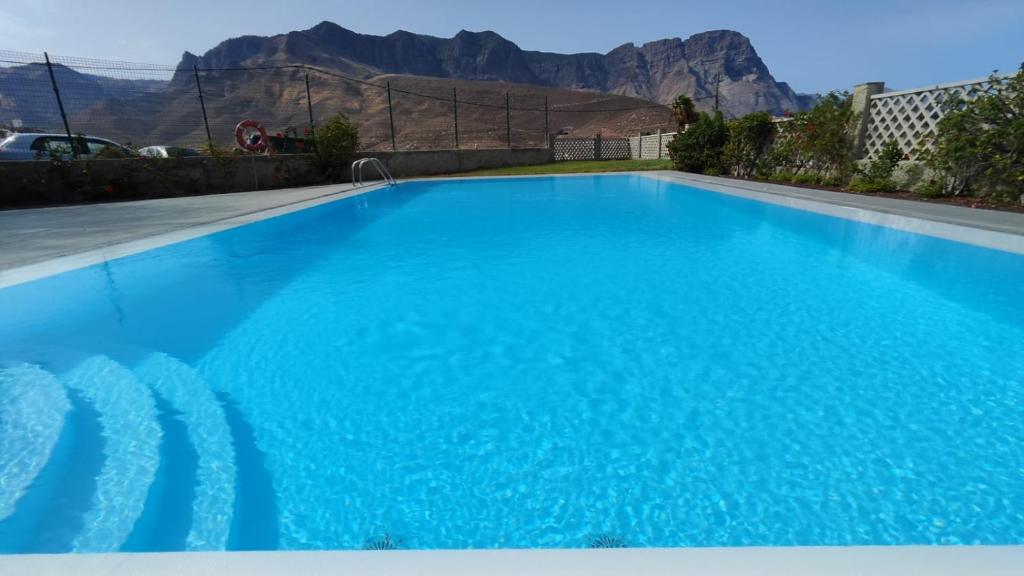 una gran piscina azul con montañas en el fondo en Agaete Sunset, en Agaete