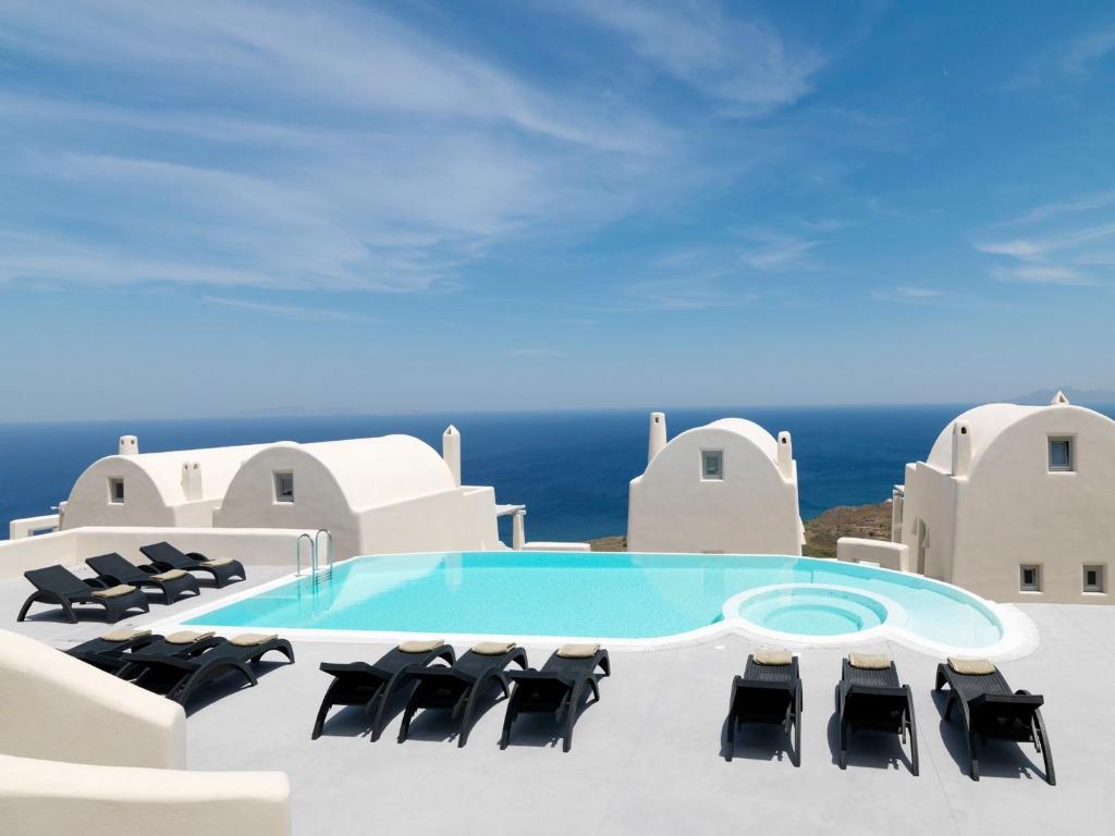 イメロヴィグリにあるDome Santorini Resort & Spaの椅子付きの建物の横にあるスイミングプール