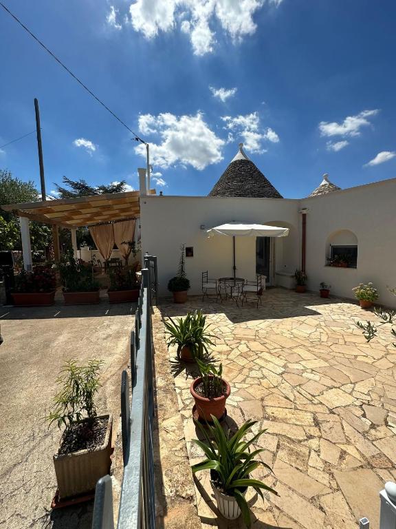 a building with a patio with plants and an umbrella at Trullo Gnoffa in La Correggia