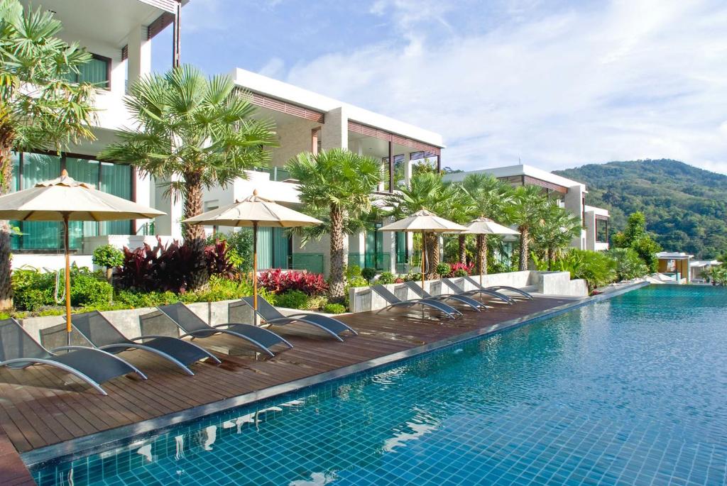 a pool at a resort with chairs and umbrellas at Club Wyndham Sea Pearl Phuket in Patong Beach