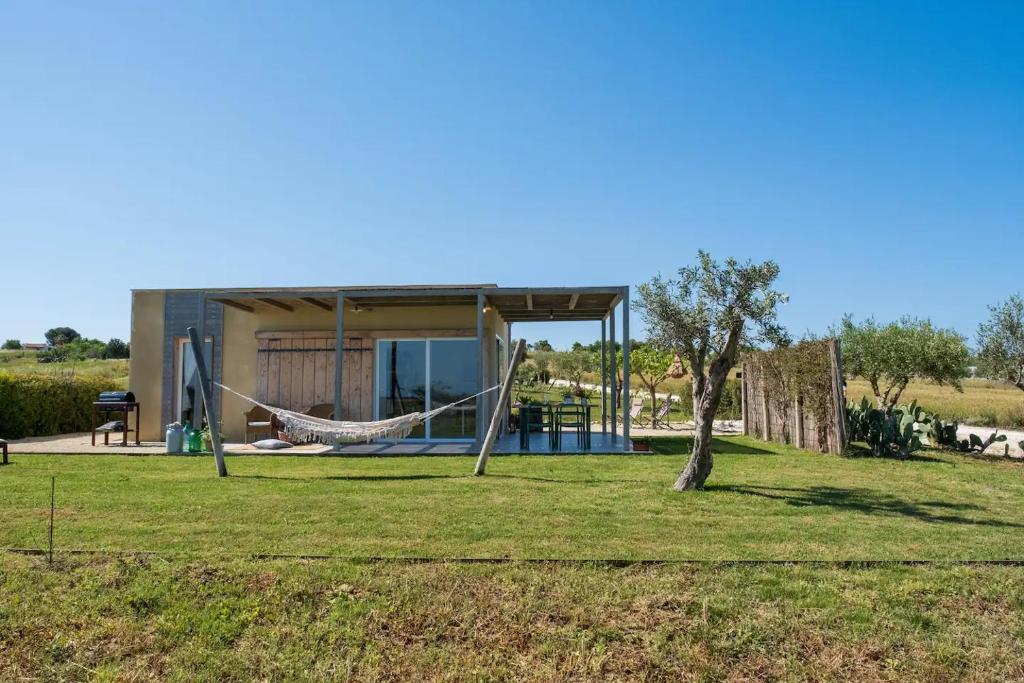 a house with a hammock in the yard at NEW Exclusive Lodges, Marzamemi, Noto in Pachino