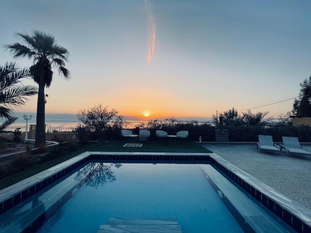 a swimming pool with a sunset in the background at The Precious Guesthouse in Sowayma