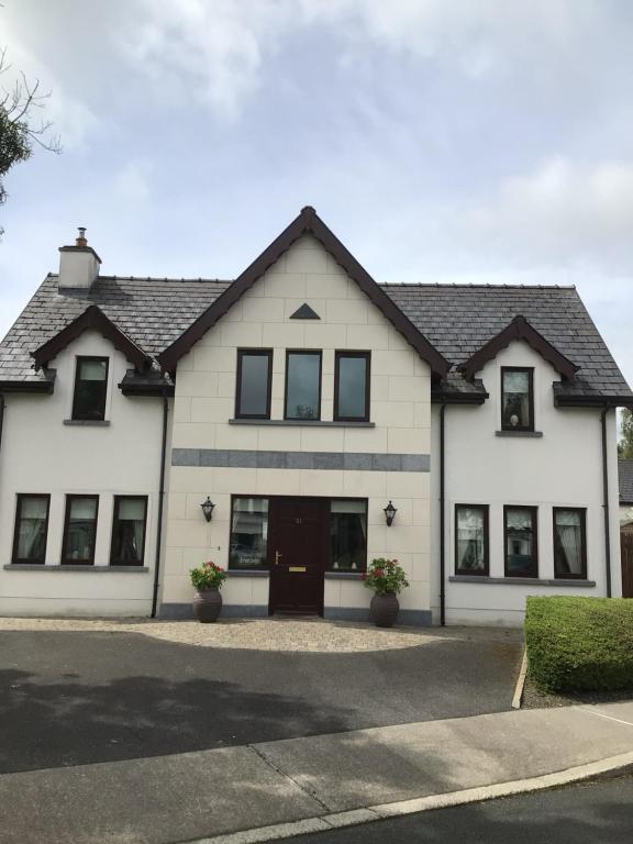 a white house with black windows on a street at Errew Lodge in Mohill