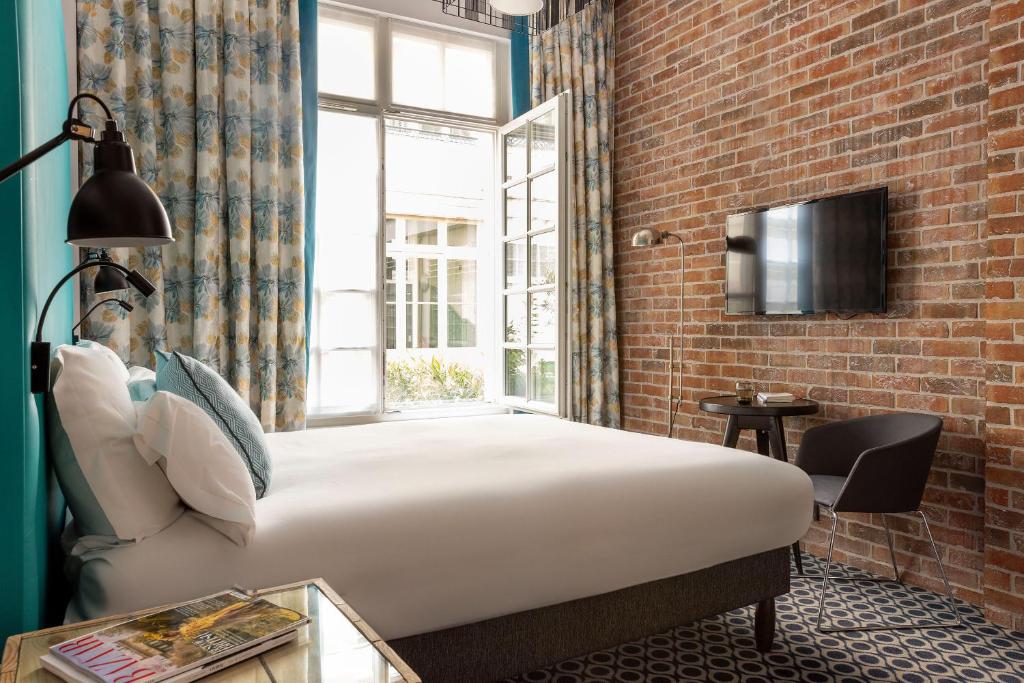 - une chambre avec un lit et un mur en briques dans l'établissement Hôtel Fabric, à Paris