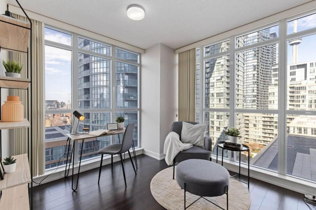 a living room with a desk and chairs and large windows at Work From home with Parking WIFI and CN Tower View in Toronto