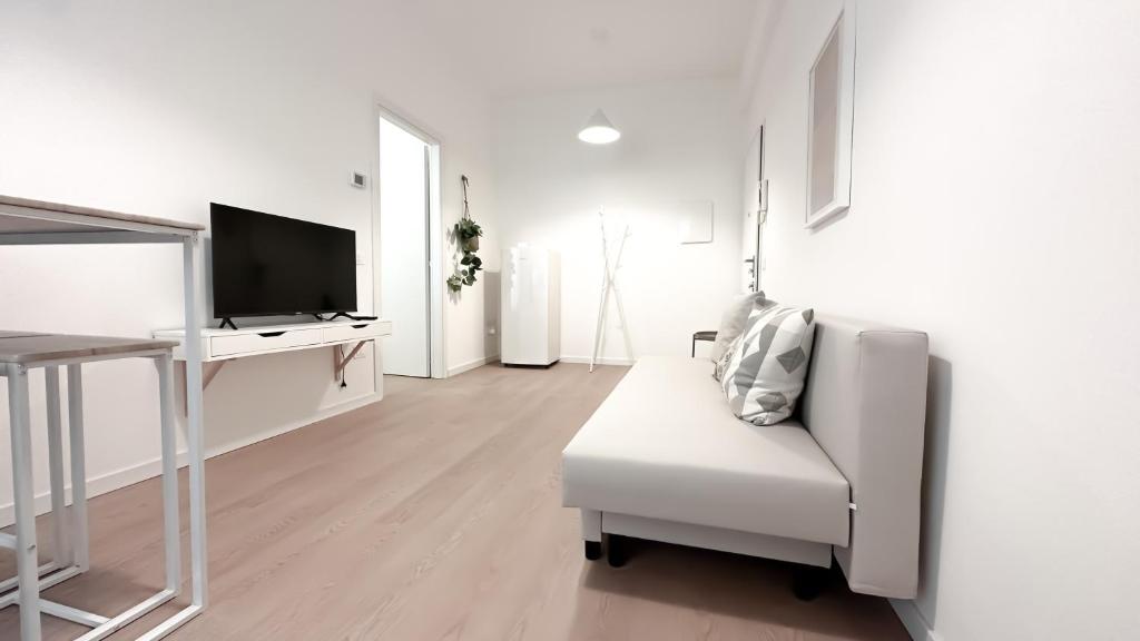 a white living room with a white chair and a television at Atelier Rimini - Affitti Brevi Italia in Rimini