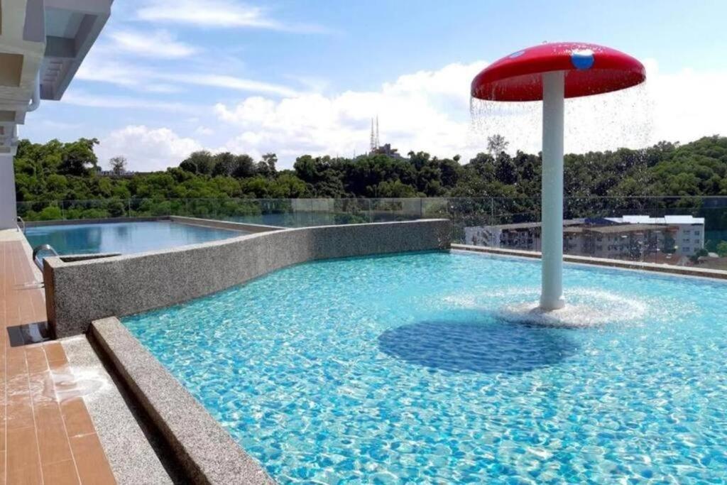 a swimming pool with a red umbrella in the water at T STAY at Icon Residence -for 1 Room Free Netflix & Pool in Kuala Terengganu