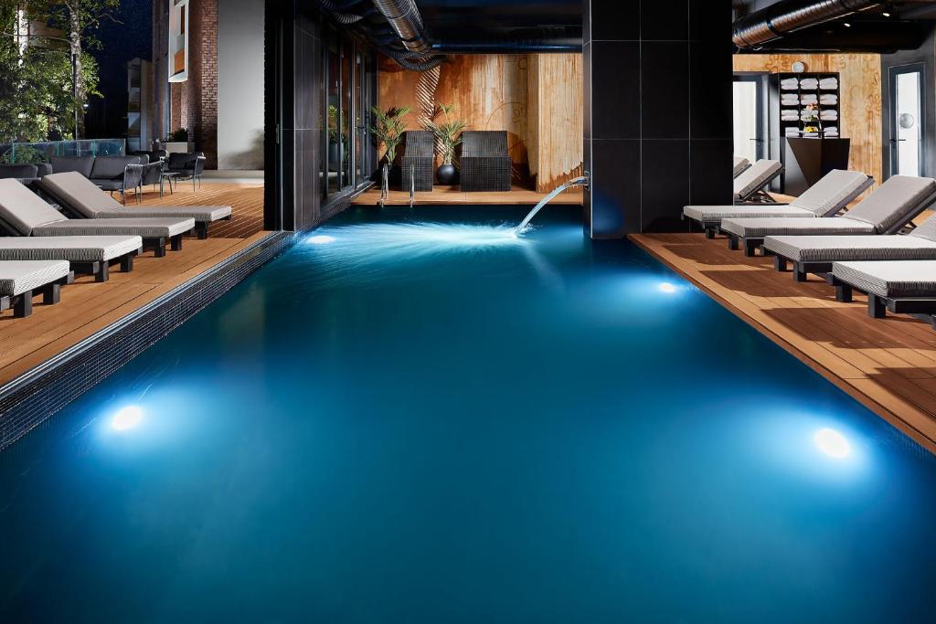 a swimming pool with blue water in a building at 21st Century Zlatibor Residence, Spa & Wellness by Adora in Zlatibor