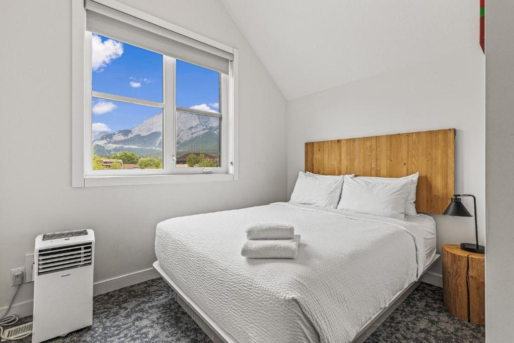 a white bedroom with a bed and a window at Basecamp Resorts Canmore in Canmore