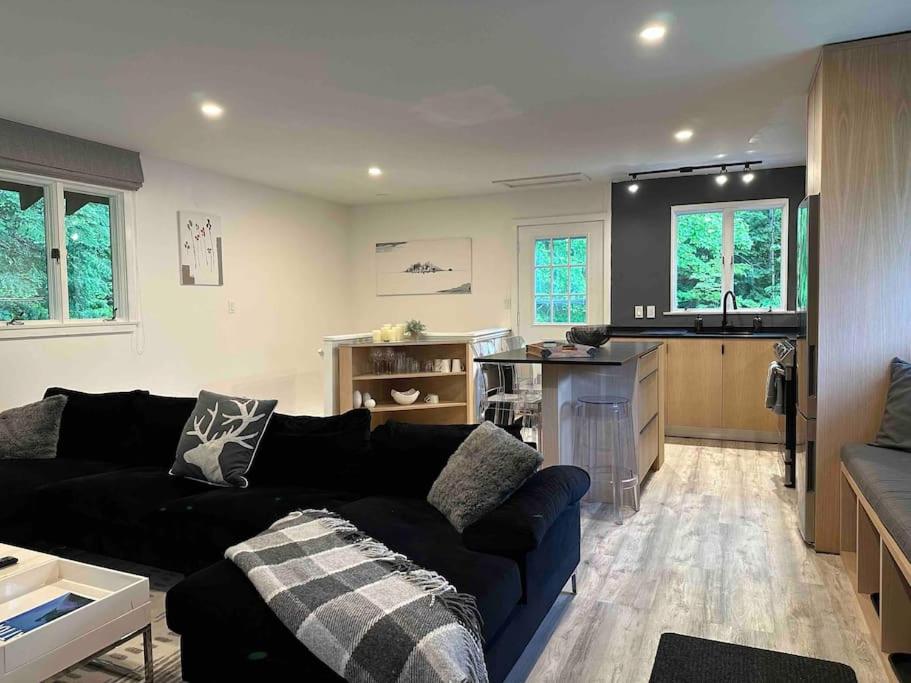 sala de estar con sofá negro y cocina en Beautiful renovated chalet mn to Stratton, en Strattonwald