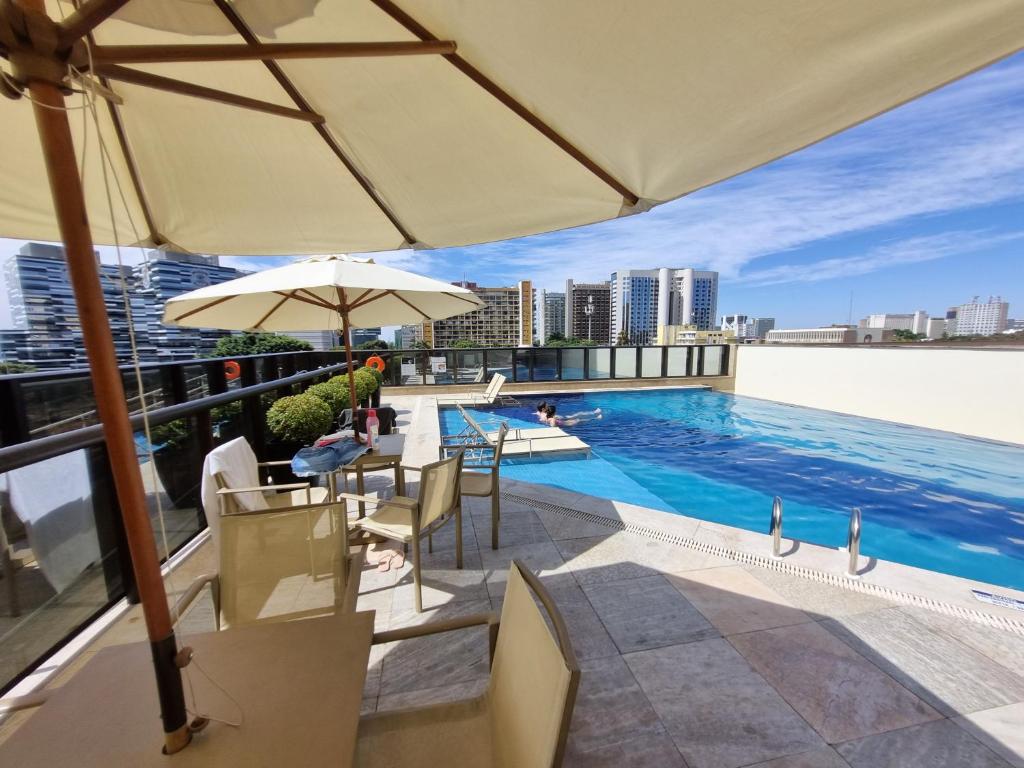 a pool on the roof of a building with an umbrella at Cullinan apart-hotel particular in Brasília
