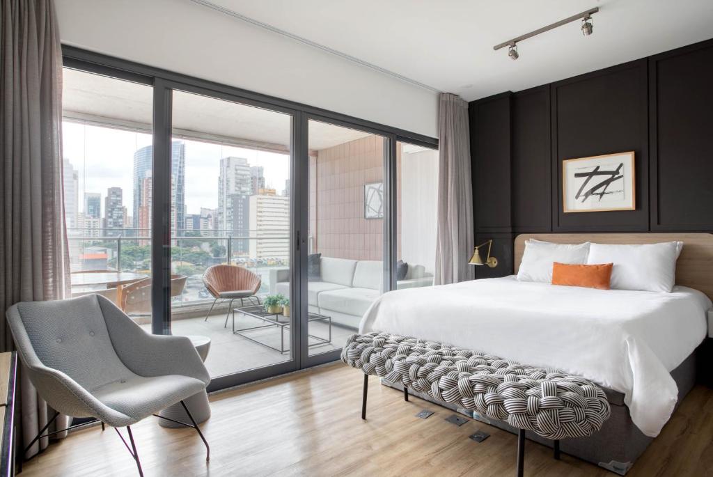 um quarto com uma cama grande e uma janela grande em Tabas - Condomínio Forma Itaim em São Paulo