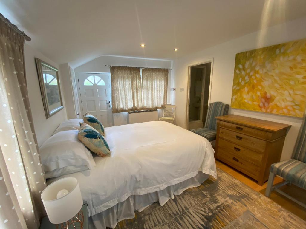 um quarto com uma grande cama branca e uma cómoda em The Guesthouse hideaway em Hordle