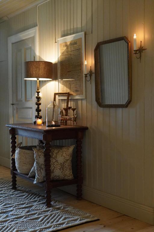 a room with a table with a lamp and a mirror at Villa Åmmeberg in Åmmeberg