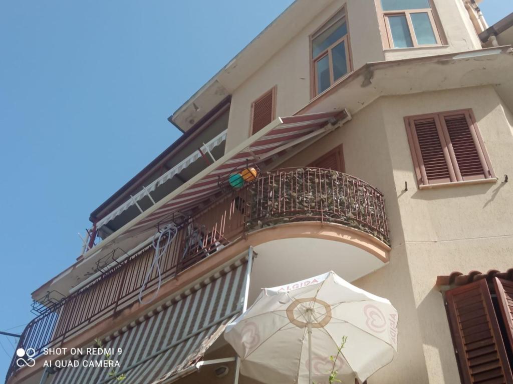 un edificio con balcón y una sombrilla delante de él en Baia blu falcone, en Falcone