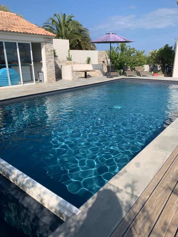 - une piscine d'eau bleue en face d'une maison dans l'établissement Magnifique maison avec vue mer hauteur de Bastia, à Bastia