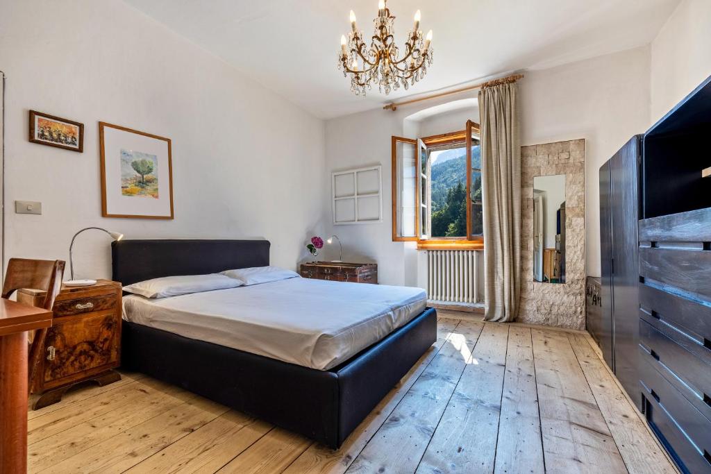 1 dormitorio con 1 cama, TV y lámpara de araña en Casa nel Borgo Iris, en Breguzzo