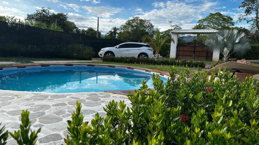 un coche blanco estacionado junto a una piscina en Casa bella de campo Wifi billar piscina bolirana !privado!, en Carmen de Apicalá